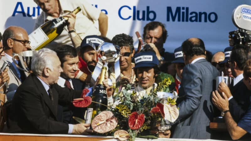 Mario Andretti celebrates victory on the podium during the Italian GP